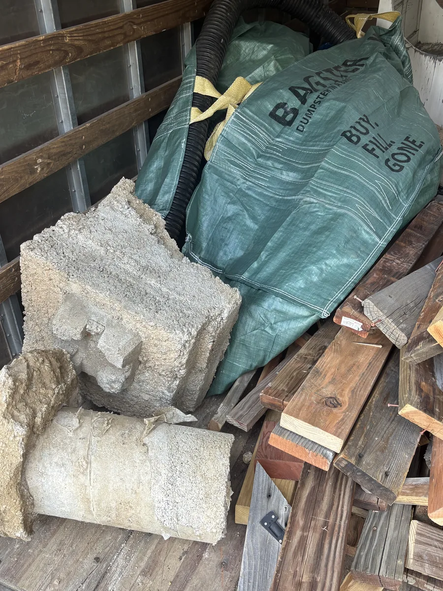 Broken concrete pier blocks and a loaded Bagster bag inside the box truck