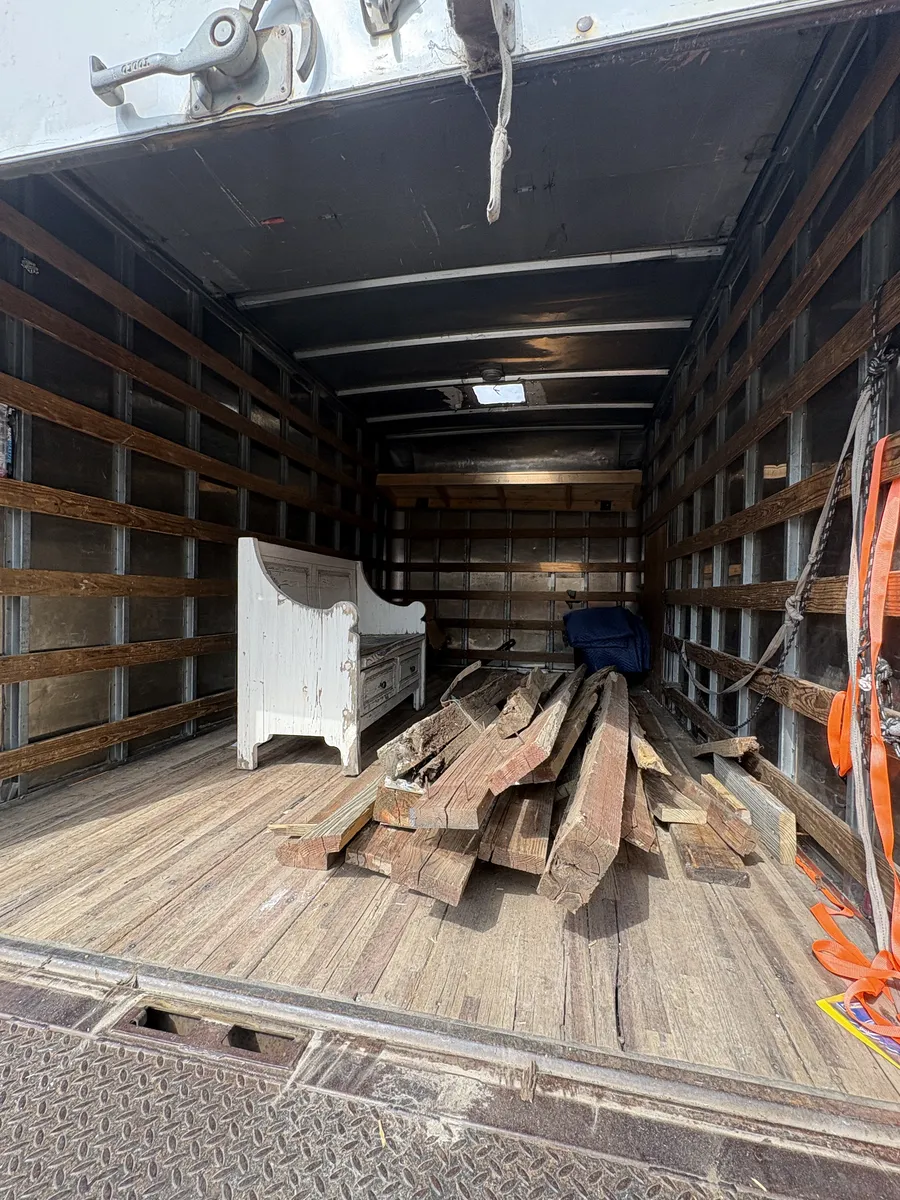 Inside the box truck loaded with the old lumber and a white wooden bench