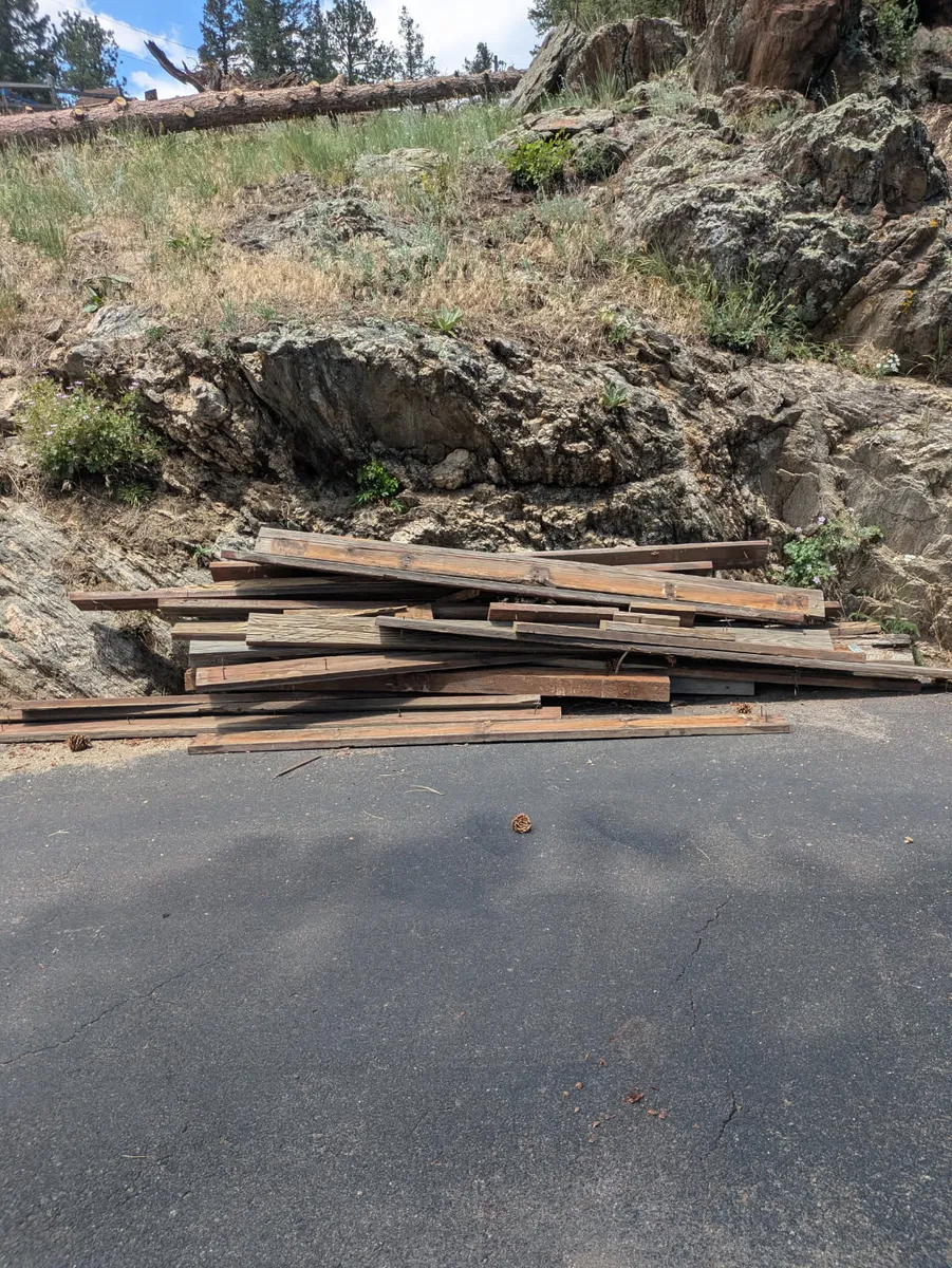 Pile of old lumber staged at the edge of a mountain driveway in Evergreen, Colorado