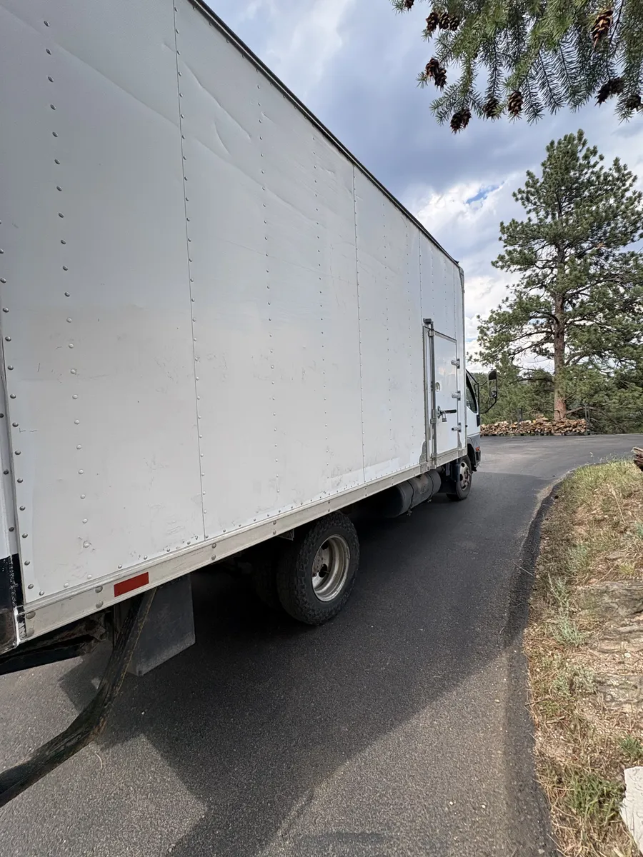 Box truck navigating a narrow paved mountain road in Evergreen, Colorado