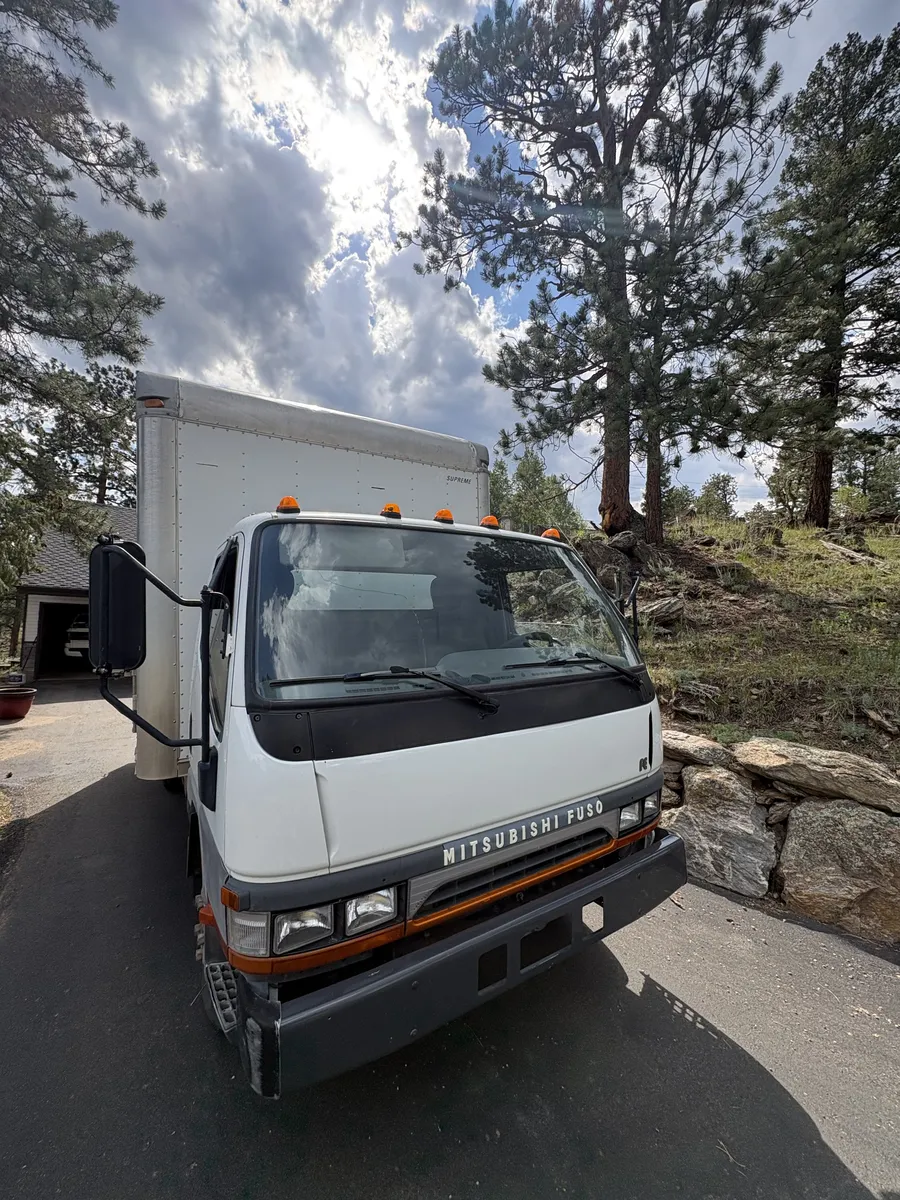Troops Junk Removal 16-foot box truck parked in a pine-lined mountain driveway in Evergreen
