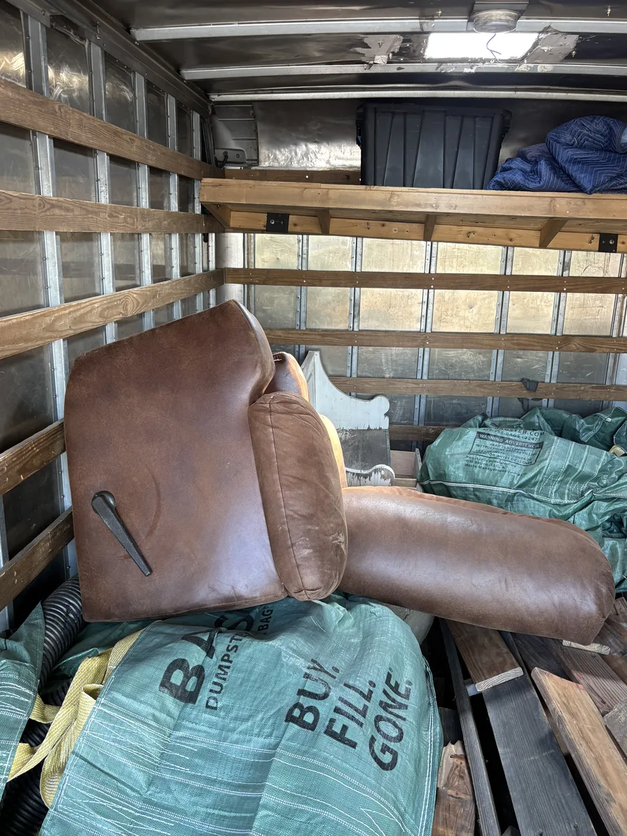 Old brown leather recliner loaded inside the Troops Junk Removal box truck